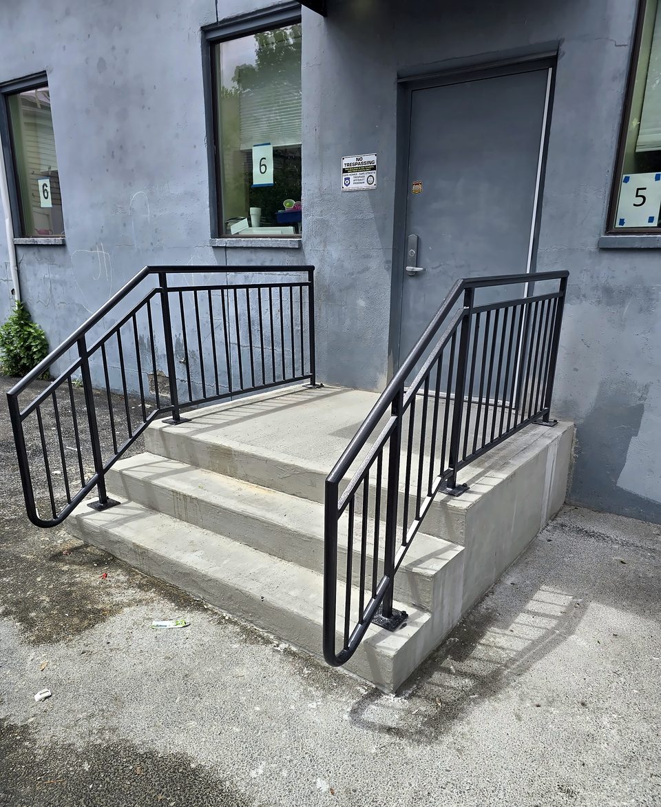 New concrete entry stairs with black steel pipe handrails at a childcare center in Albany
