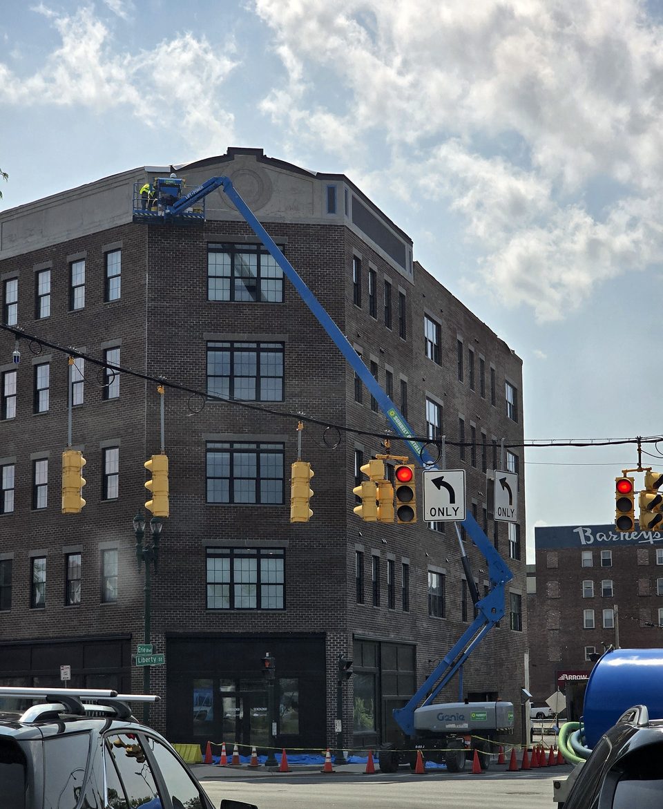 Crew on a boom lift installing prefabricated EIFS panels on a downtown building