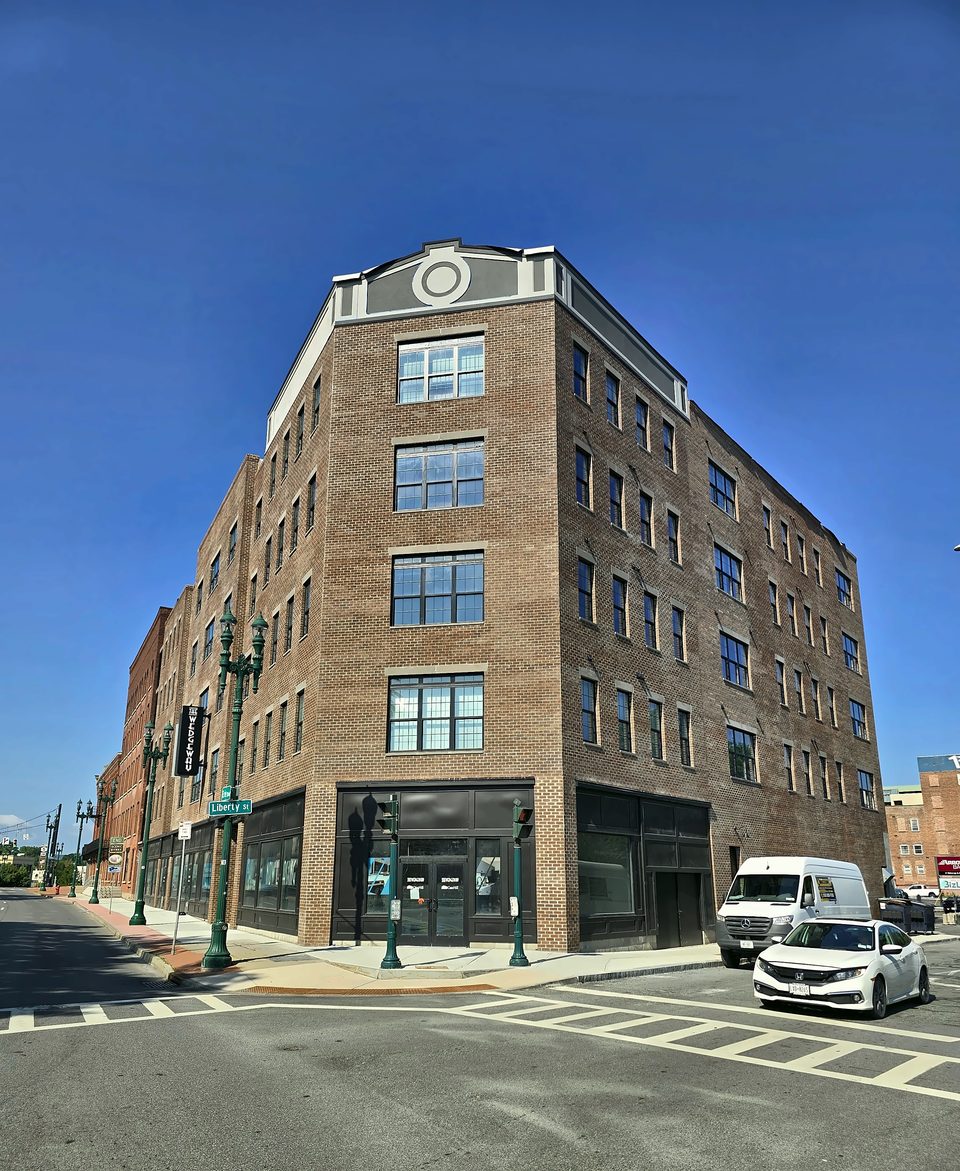 Five-story brick building in downtown Schenectady with its new EIFS top band finished, blue sky