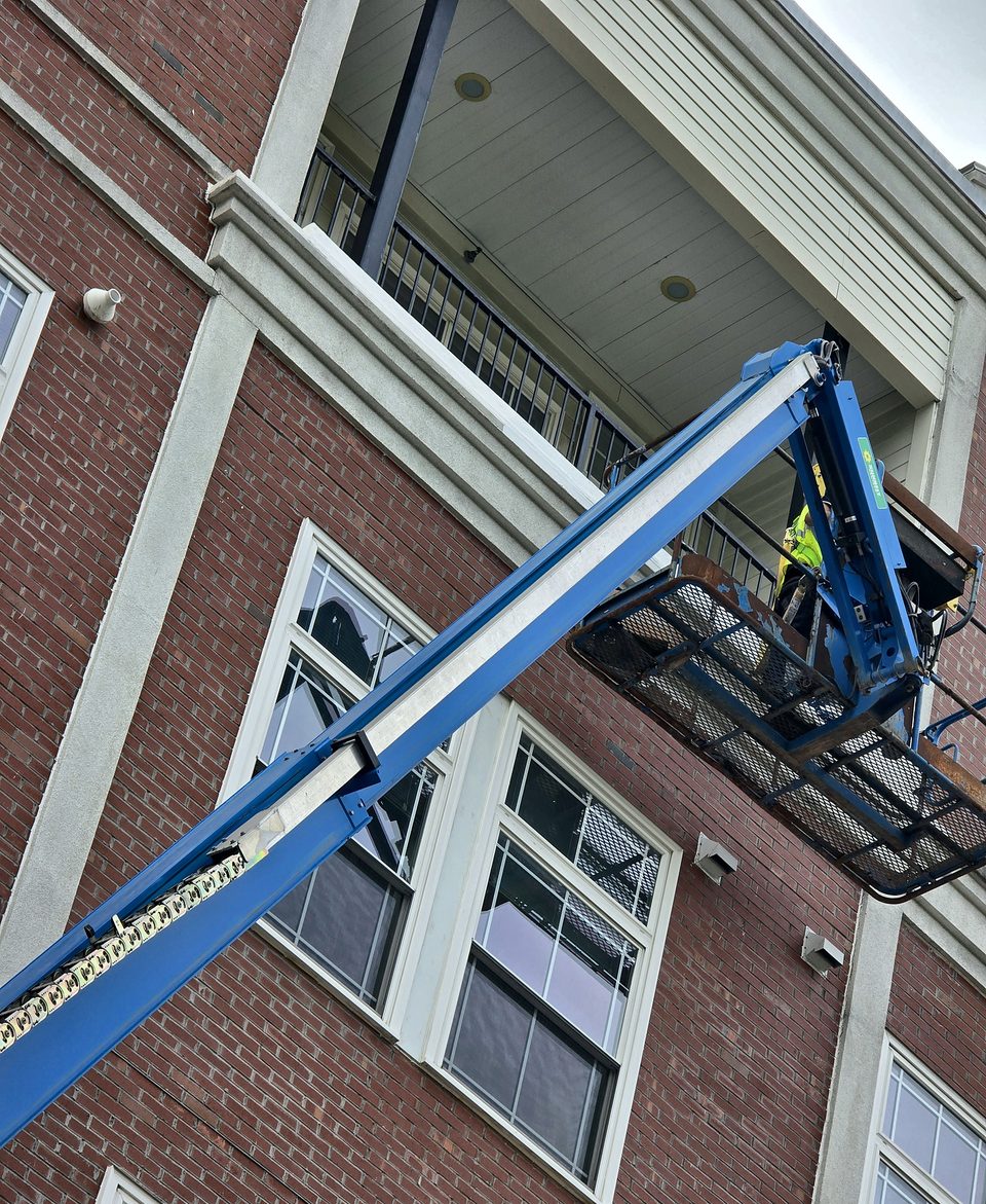 Boom lift raised to a balcony on a brick apartment building in Albany