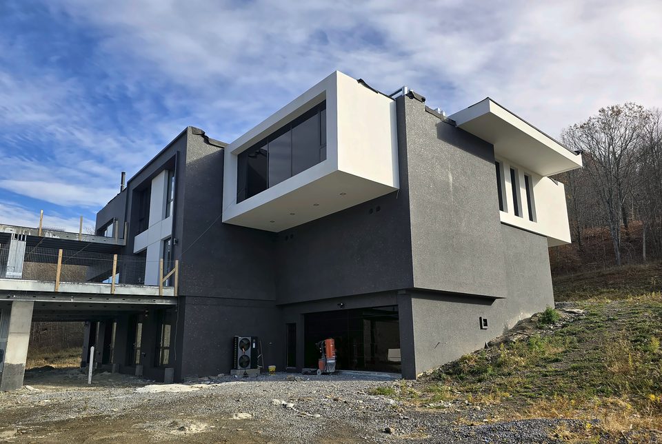 Modern hillside residence with a two-tone white and charcoal EIFS finish in the Catskills